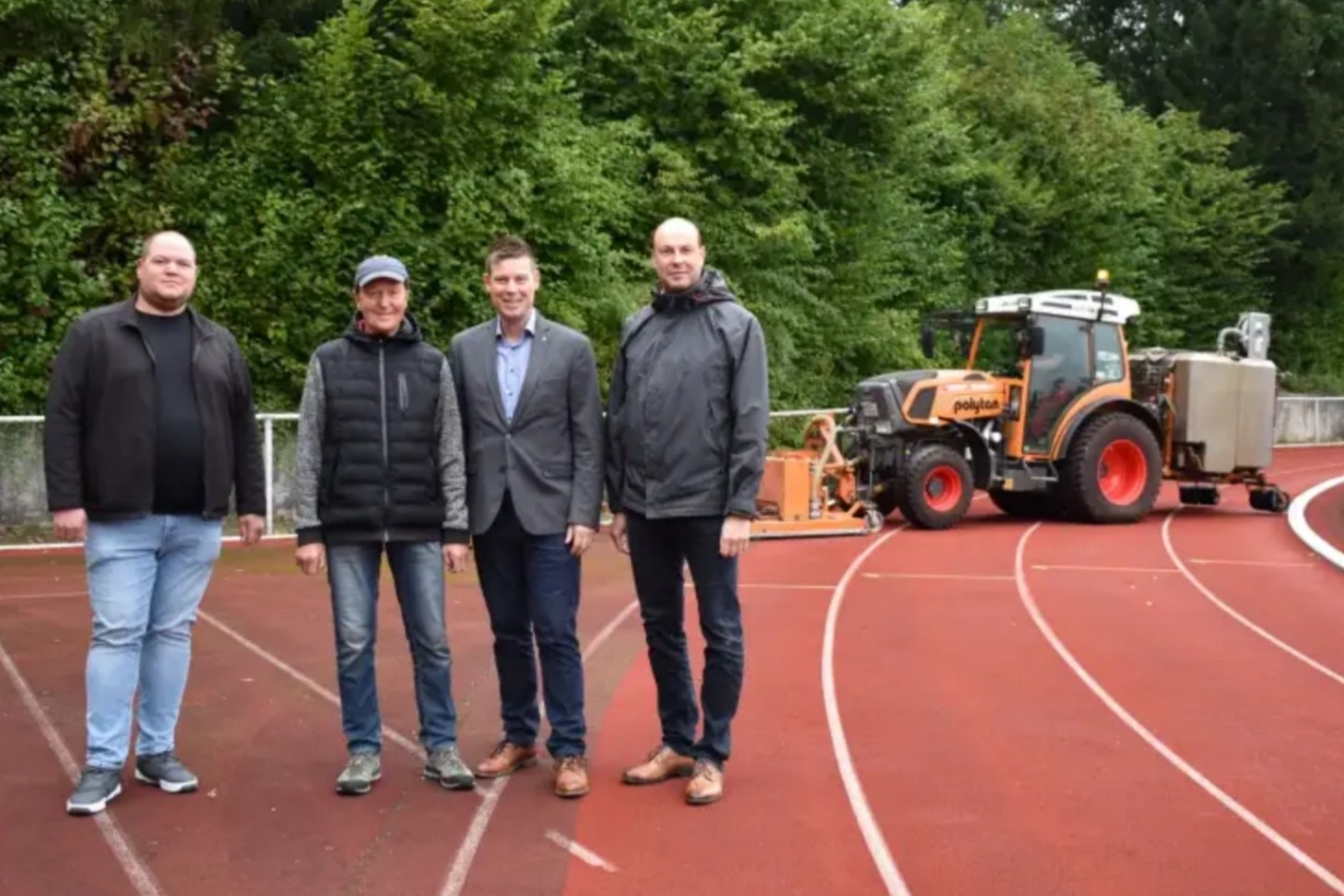 Thomas Sonntag (Amtsleiter Tiefbau), Peter Kufner (1. Vorsitzender TV Jahn), Michael Scholle (1. Beigeordneter) und Uwe Damer (Sportdezernent) auf der Tartanbahn im Iburgstadion. In der Kurve sieht ma